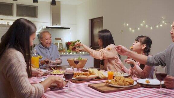 幸福的家庭时间和关系亚洲大家庭有一个小聚会一起在家里吃东西爷爷很高兴看到他的孩子和侄子在家里的餐桌上吃饭分享食物