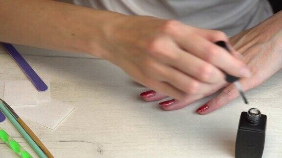 女孩给自己做了一个美甲用红色的指甲油涂了她的指甲