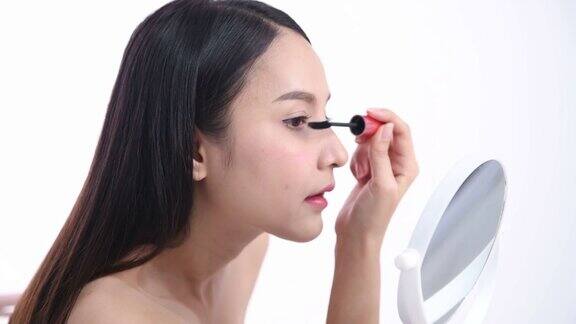 一位亚洲女性博主正在展示如何化妆和使用化妆品在摄像机前录制视频直播流媒体在工作室