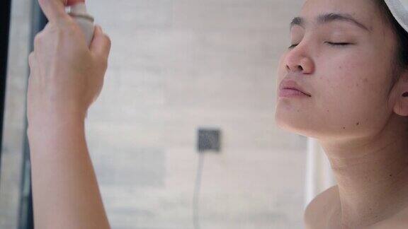 亚洲妇女用矿泉水喷雾进行面部护理