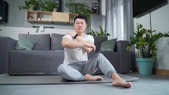 年轻的亚洲男子在室内伸展背部疼痛运动健身男性苦于感到疼痛突然肩膀和关节疼痛肌肉拉伤