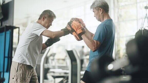 亚洲华人高级男子练习拳击对打在健身房例行的周末活动