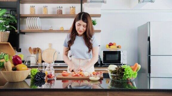 一个快乐的年轻亚洲女人准备健康的沙拉与蔬菜在砧板上的家庭厨房柜台食物烹饪夫妻夫妻在一个良好的关系实时4k视频