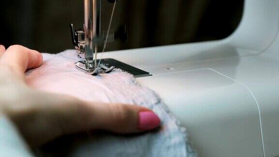 特写女人的手在缝纫机上缝制织物