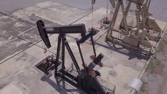 无人机飞行经过工作抽油机工业油泵千斤顶与油田钻机一起工作为化石燃料能源抽送原油