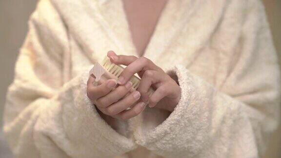 年轻美丽的女人走出淋浴用指甲刷照顾她的手