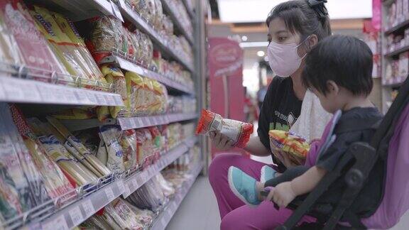 亚洲母子在超市购物推着婴儿购物车