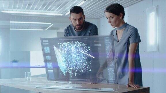 未来概念:男女计算机工程师在全息显示计算机上工作时谈话屏幕显示交互式神经网络人工智能项目用户界面
