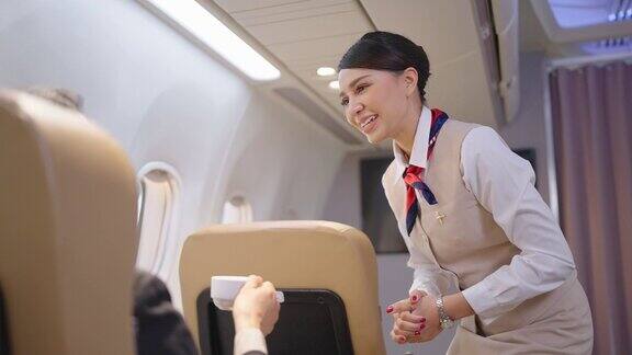 友善的亚洲女空姐在飞机上为乘客提供食物、饮料和交谈航空公司服务