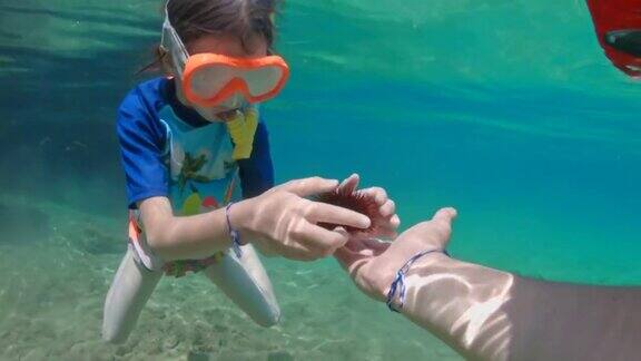 小女孩在水下探索清澈的蓝色海洋