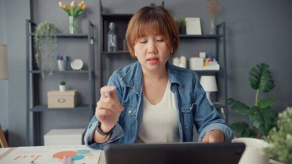 亚洲女商人使用平板电脑与同事视频通话在家里的客厅工作远程工作场所保持社交距离隔离以预防冠状病毒