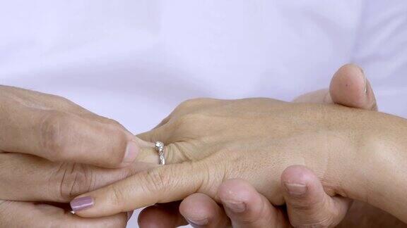 靠近男人的手把结婚戒指戴在女人的无名指上
