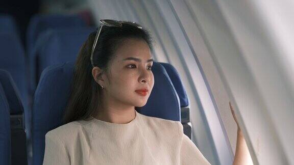 一个亚洲女人坐在飞机上望着窗外