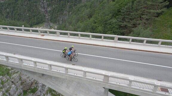 空中拍摄:在峡谷上方的桥上骑公路自行车的三个人