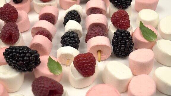 树莓黑莓浆果串和棉花糖放在野餐和聚会的白色桌子上