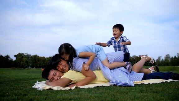 快乐的亚洲家庭在公园里挤在爸爸身上
