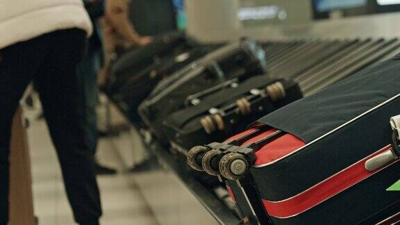 不知名的妈妈在机场的行李传送带上拿起他的旅行包