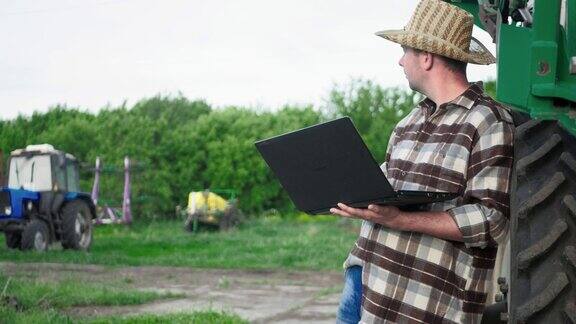 智能农业在农业活动中应用现代技术会电脑的年轻地主一名技术工人带着笔记本电脑在拖拉机旁边工作概念现代科技