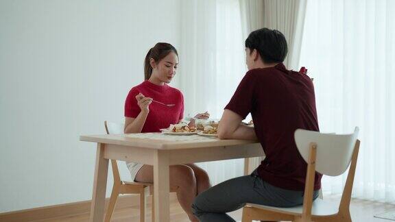 一对年轻的亚洲夫妇正坐在家里的餐桌旁一起享用午餐