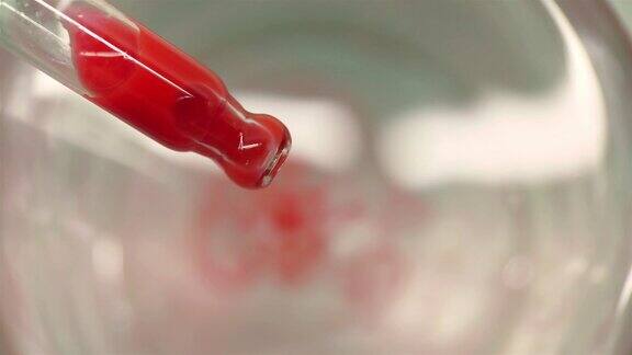 一滴红色的液滴从移液管中滴入水中
