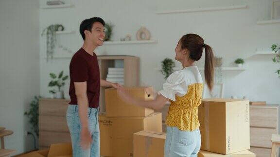 一对年轻的亚洲夫妇正在帮忙搬运要堆放在客厅里的包裹
