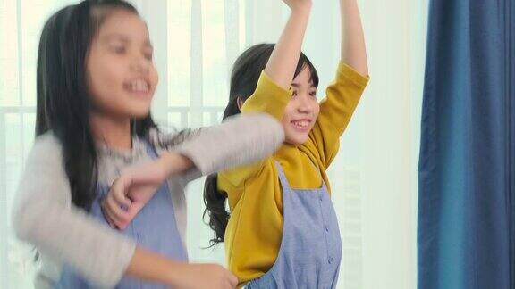 亚洲女性儿童兄弟姐妹一起在客厅里玩姐妹在家里一起跳舞家人在家里人