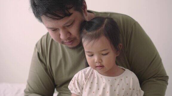 父亲和女儿在床上一起享受一本儿童读物