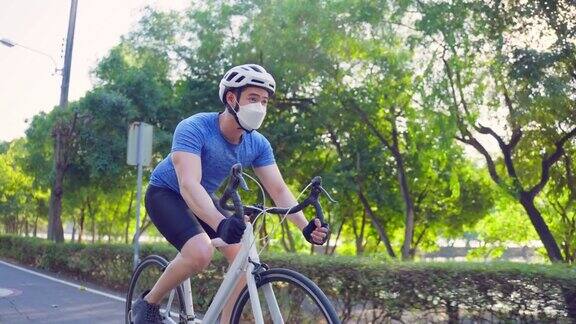 亚洲年轻运动男性戴口罩在公园里骑自行车迷人的运动员肌肉男运动服装骑自行车锻炼的健康和保健健康的晚上