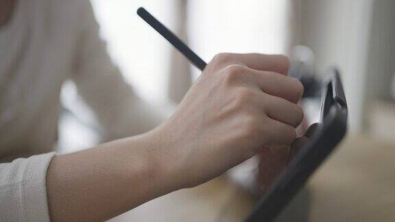 在数字平板上使用数字笔的手的特写