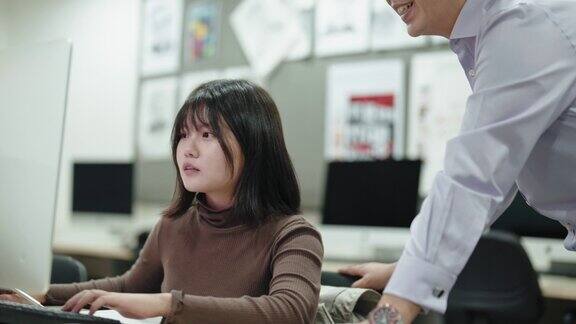 亚洲男导师在计算机实验室教室的显示器上看着女成年学生的工作解释项目分配简报