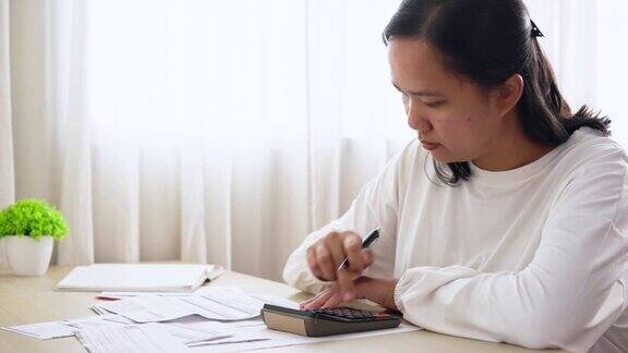 亚洲妇女使用计算器管理家庭财务和账单报表家庭财务规划