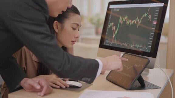 股票经纪人团队正在办公室里讨论屏幕上显示着股票市场图表高级分析金融人向初级分析交易员讲解如何分析图表和投资金融交易员