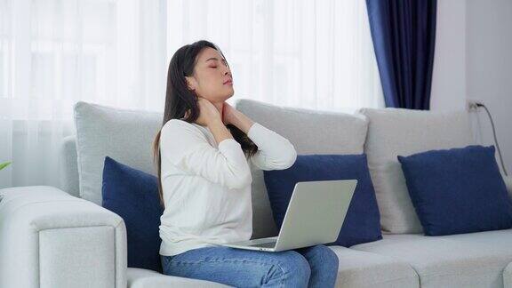 办公室综合症概念年轻的亚洲妇女在长时间使用笔记本电脑后感到颈部和肩部疼痛她伸展筋骨以放松肌肉