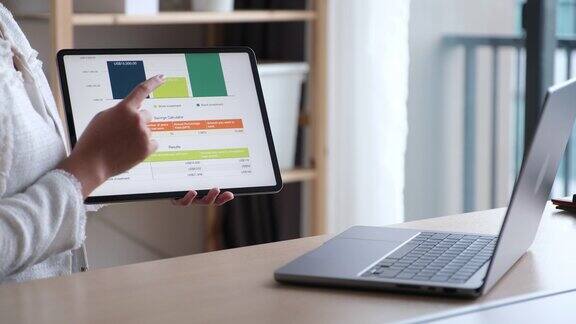 近距离理财规划师手持平板电脑通过笔记本电脑电话会议讲解个人储蓄