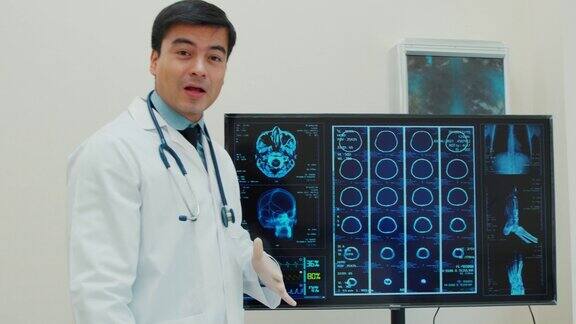一名白人男性医生在电脑上分析MRI头部扫描的4k镜头拍摄了视频会议期间对着摄像机讲话的画面