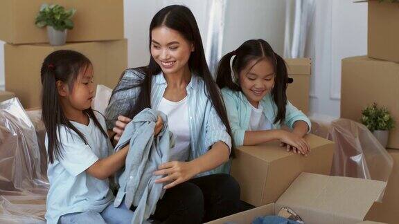 亚洲母亲和女儿在室内移动箱子包装衣服