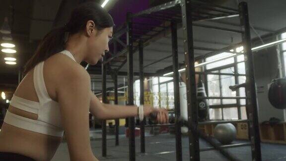 女子训练做格斗绳锻炼锻炼手臂和有氧运动的健身房锻炼健身人士在健身房用格斗绳练习