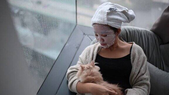一个亚裔中国少女在卧室里和她的猫做水疗面膜