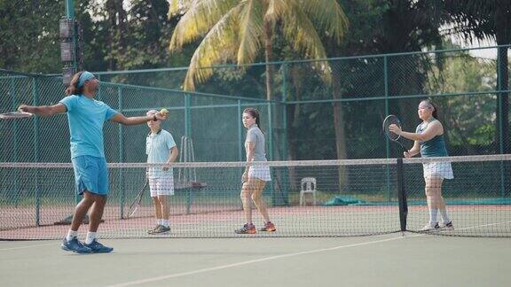 亚洲网球教练展示成人学生在网球场拿球拍