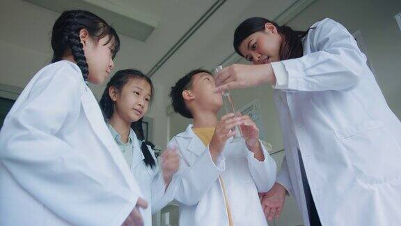 教师授课并向小学生讲解化学他们在学校实验室的烧杯中学习科学和化学混合