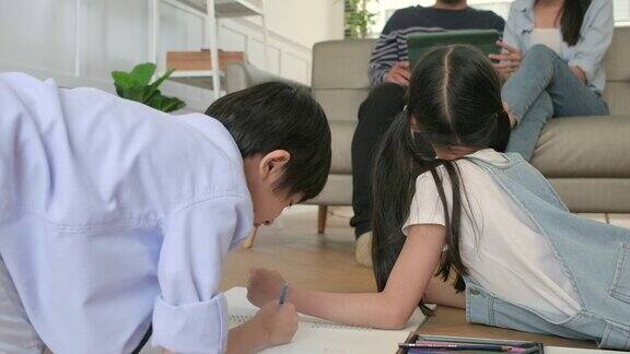 亚洲的兄弟姐妹一起用彩色铅笔画画父母在沙发上休息