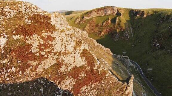 日落时分无人机沿着石灰石悬崖边缘沿着英国温纳茨山口山谷飞行