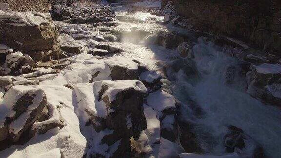 无人机漂浮在积雪的岩石上揭示冬季汹涌的河流