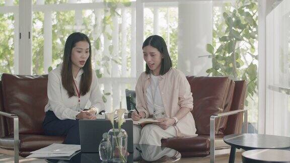 两个亚洲女商人同事在工作场所聊天