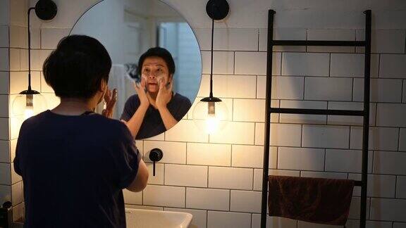 亚洲华人在厕所里用面膜对着镜子看