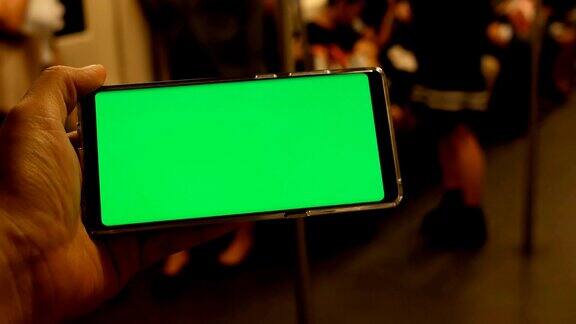 一名男子在火车上拿着绿色屏幕的手机
