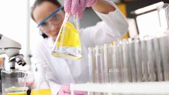 科学家戴着手套手拿着装有黄色液体的无菌烧瓶