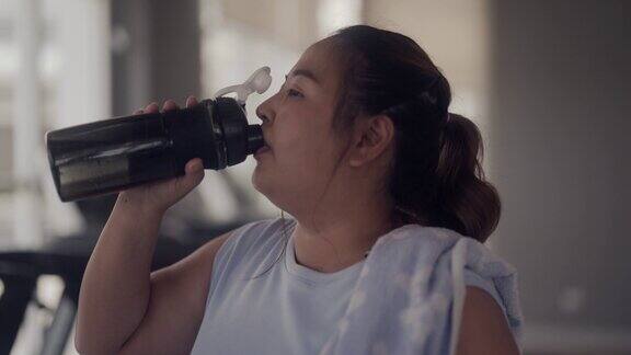亚洲大码女人在健身房喝水
