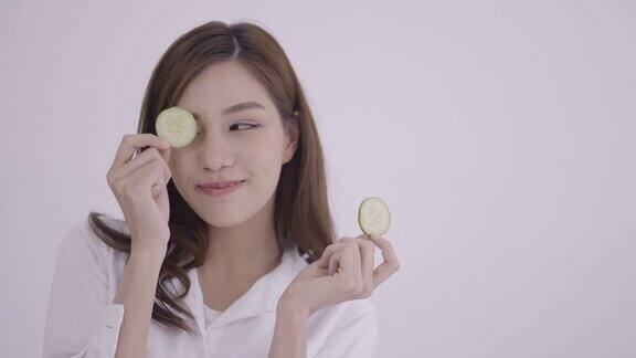 一个漂亮的年轻女人用一片黄瓜片遮住了眼睛
