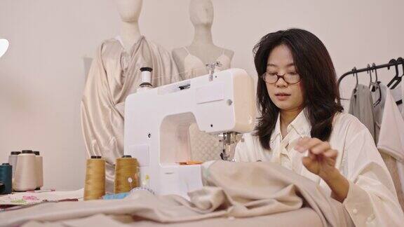 亚洲服装设计师正在使用电动机器缝制衣服的4k视频片段在办公室在家里专业手工业概念小型企业